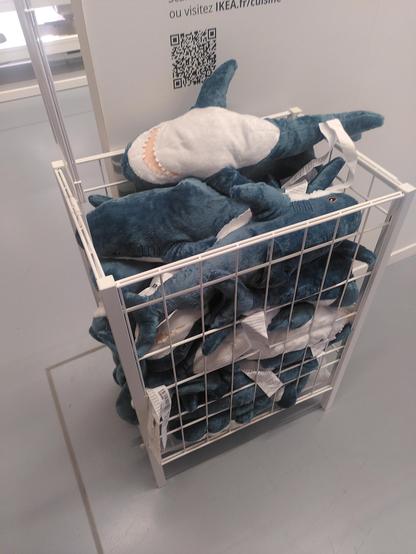 A stack of shark plushie in a cage