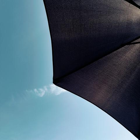 An image of an umbrella on a sunny day - the black image of the umbrella and a blue sky
