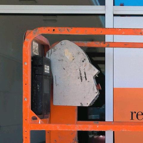 Close up on the silhouetted face. There's a big red button that makes a mouth, a projecting nose with toggle switches that look like nasal hair, a small hole about where the eye would be, and scuff marks like cheek wrinkles. It is entirely possible this looks like a face accidentally or deliberately