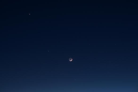 In later twilight all the yellow, orange, and rad has faded. It's now the blue hour. The moon's earthshine stands out against the deep blue sky. Brilliant Venus is in the upper right corner. Closer to the moon, Jupiter is the second brightest 'star' in the image. Below the moon is Mercury. The right half of the frame feature the stars Castor and Pollux.