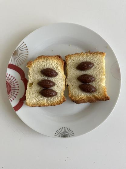 Assiette avec deux tranches de focaccia agrémentées de trois pépites de chocolat noir de Sao Tome.
Grillées au four.