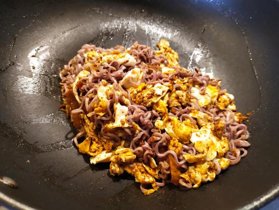 Foto de una pila de tallarines instantáneos, huevo y kimchi salteados juntos en el fondo de un wok.