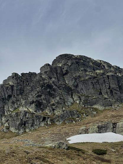 Gnarly looking mountainside with snow in the foreground.