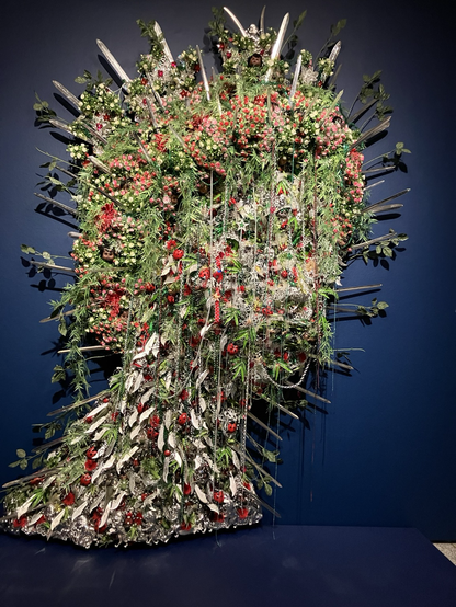 Assemblage of red green silver bric-a-brac that makes a queen head