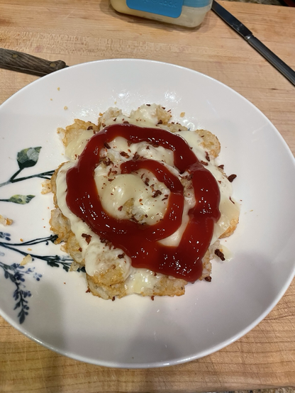 Tater tots covered in melted cheese with a spiral of ketchup on top.  Sprinkled with flecks of fake bacon bits. Dinner of champions.