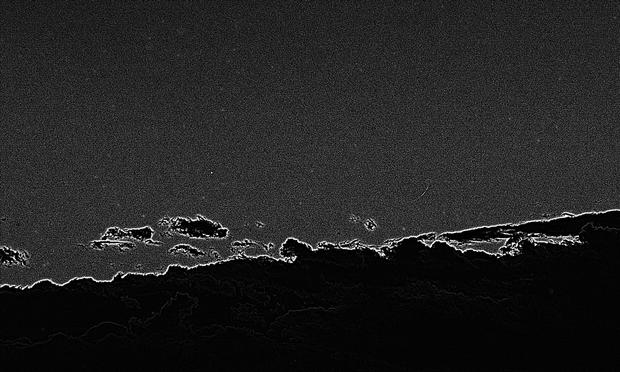 A noisy monochrome image that barely shows the crescent moon and Jupiter just above low clouds. Heavy image processing has 'flattened' the gradient in the twilight sky but made the objects more visible.