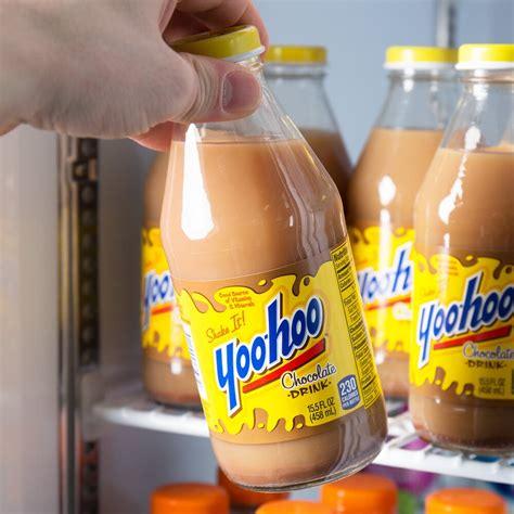 Someone grabbing a Yoo-Hoo bottle from a store fridge. It looks like watery chocolate milk with sediments at the bottom of the wide neck glass bottle. The label is yellow with a blue all lowercase logo, red underlined, and the message "shake it" above the "yoo"