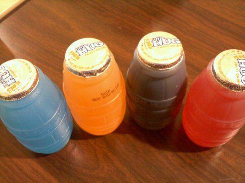 Four bottles of "Little Hug" drinks. These are wide neck polyethylene bottles, the same not quite clear plastic used for milk jugs, shaped and ridged like a small barrel. The label with the name and ingredients is the glued on foil lid. Once opened, you can't close these. There are four artificial flavors in different artificial colors here, blue orange, purple, and red. They look (and taste) like the liquid in the large condiment packet[*] frozen "Fun Pops" squeeze tubes.

[*] Those freeze yourself ice pops in plastic tubes look like condiment packets because they share the same inventor, made using basically the same equipment. Howard Epstein of the Kari-Out soy sauce company