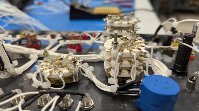 Close up picture of some of the rotary switches from the side. One of them has 3 layers with multiple leads on each layer. The wire is soldered to each lead them bent straight down and zip tied to form a column of wires for each rotary position