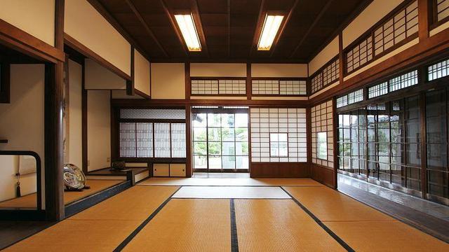 A washitsu (traditional Japanese-style room) with tatami mat floor and sliding paper doors. Everything is rectangular, with clean lines and a near symmetrical layout. Black, brown, beige, and caramel colors predominate. It's stunning.