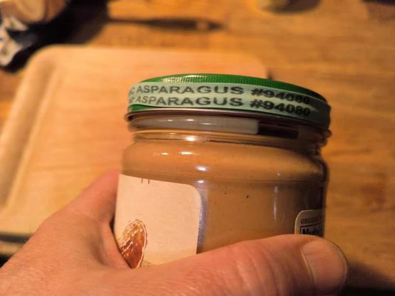 Peanut butter jar in hand with a rubber band labeled "asparagus" around the lid