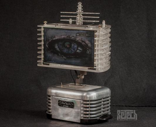 A tabletop device with a chrome base and plexiglass top sporting a 10" colour screen. Both sections are mid century modern in looks with stylish fluted sided.