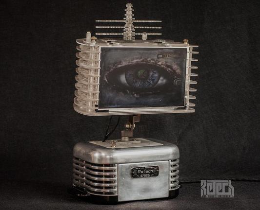 A tabletop device with a chrome base and plexiglass top sporting a 10" colour screen. Both sections are mid century modern in looks with stylish fluted sided.