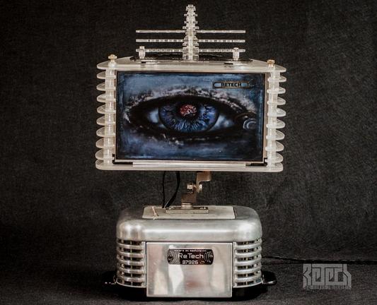 A tabletop device with a chrome base and plexiglass top sporting a 10" colour screen. Both sections are mid century modern in looks with stylish fluted sided.