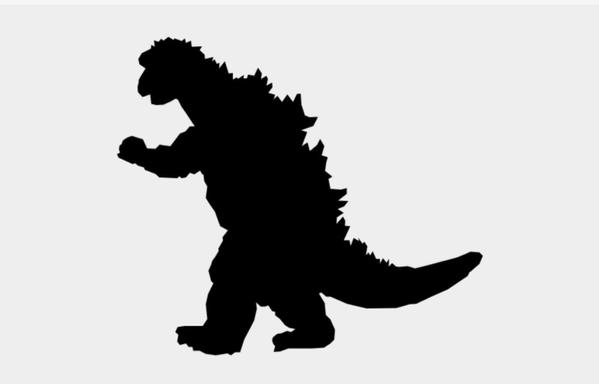 A photo of a black silhouette cut out of Godzilla walking to the right with one arm outstretched. It is on a plain white background.