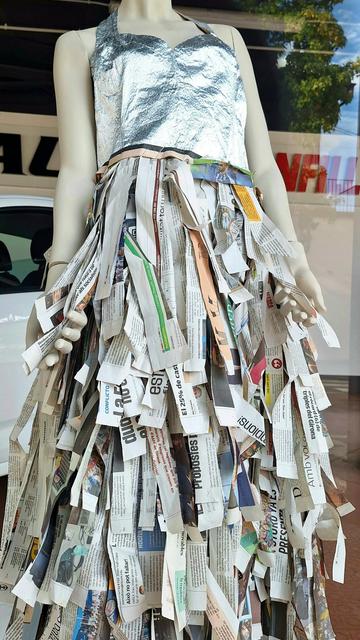 The photograph shows a mannequin wearing an outfit in which the skirt is made from strips of newspaper. It is one of the award-winning dresses in a paper dress competition held annually in Olot.