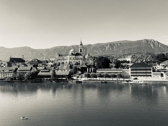 A black and white picture of the Aare river with the old town in the back, overlooked by the cathedral. In the dar distance, the Jura mountains and Weissenstein in particular.