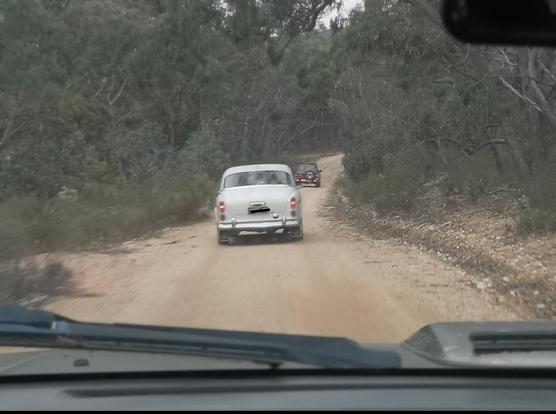 1960s Volvo out 4x4ing on a bush track seen through front window of vehicle behind.