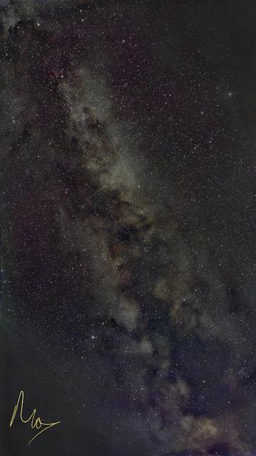 A portrait orientation colour photo of the night sky. The image is full of stars and diagonally from top left to bottom right is a close-up of part of the Milky Way. Top right and bottom left corners have been heavily edited to remove local light pollution.