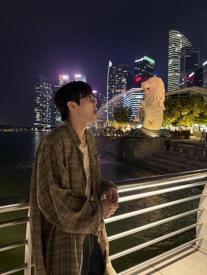 Night photo in Singapore with kpop star SUHO looking like a stone mer-lion is spitting a stream of water into his mouth.