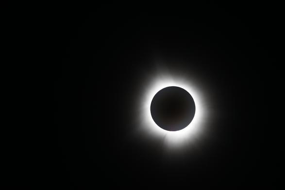 A total solar eclipse with the solar wind streaming out of a pitch black hole on a pitch black canvas. It's eerie and awe inspiring.