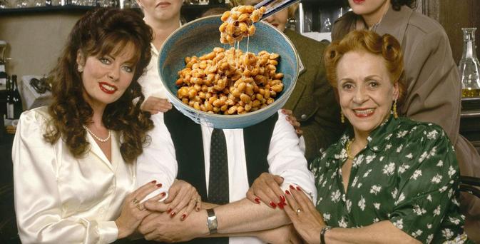 A photo of some characters from the British sitcom Allo Allo. Yvette the waitress is on the left, Edith Artois is on the right, and Rene Artois is in the center, but a bowl of natto (fermented soybeans) has been superimposed over his head.