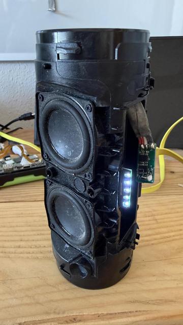 Foto of the disassambled JBL 3 Charge with the charging ciŕcuit plugged in. The lights are on an the speaker is connected.