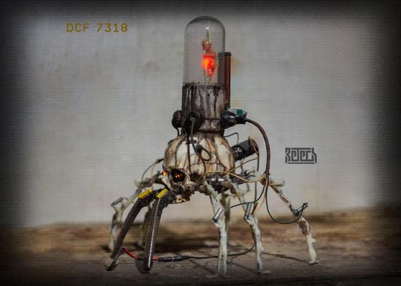 A skull with mech legs and a foetus in a clear chamber on top. Various wires and other bits are connected.