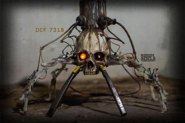 A skull with mech legs and a foetus in a clear chamber on top. Various wires and other bits are connected.