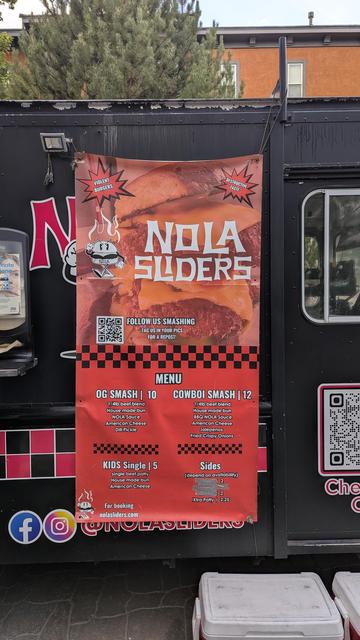 Picture of a food truck menu for "Nola Sliders". Menu items are an 'OG Smash' slider, a 'Cowboi Smash' slider, and a 'Kids Single'. The sides menu is covered with duct tape.