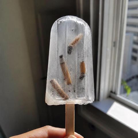a chopstick icicle from clear water with siggaret buts in them, standing for how society feeds us crap nomatter what we do