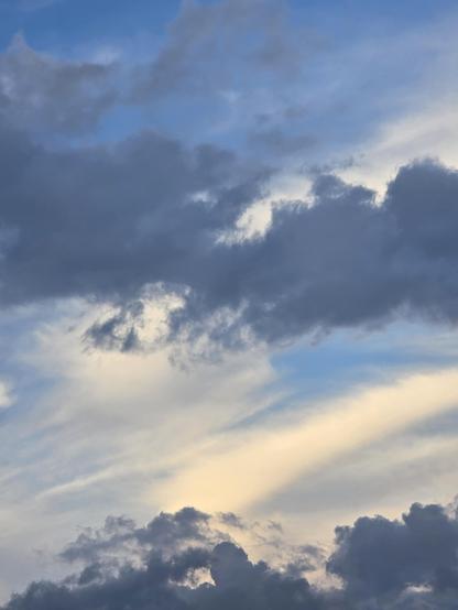 Grey clouds cur across white whispy clouds in blue sky. 
Like blue camo.
