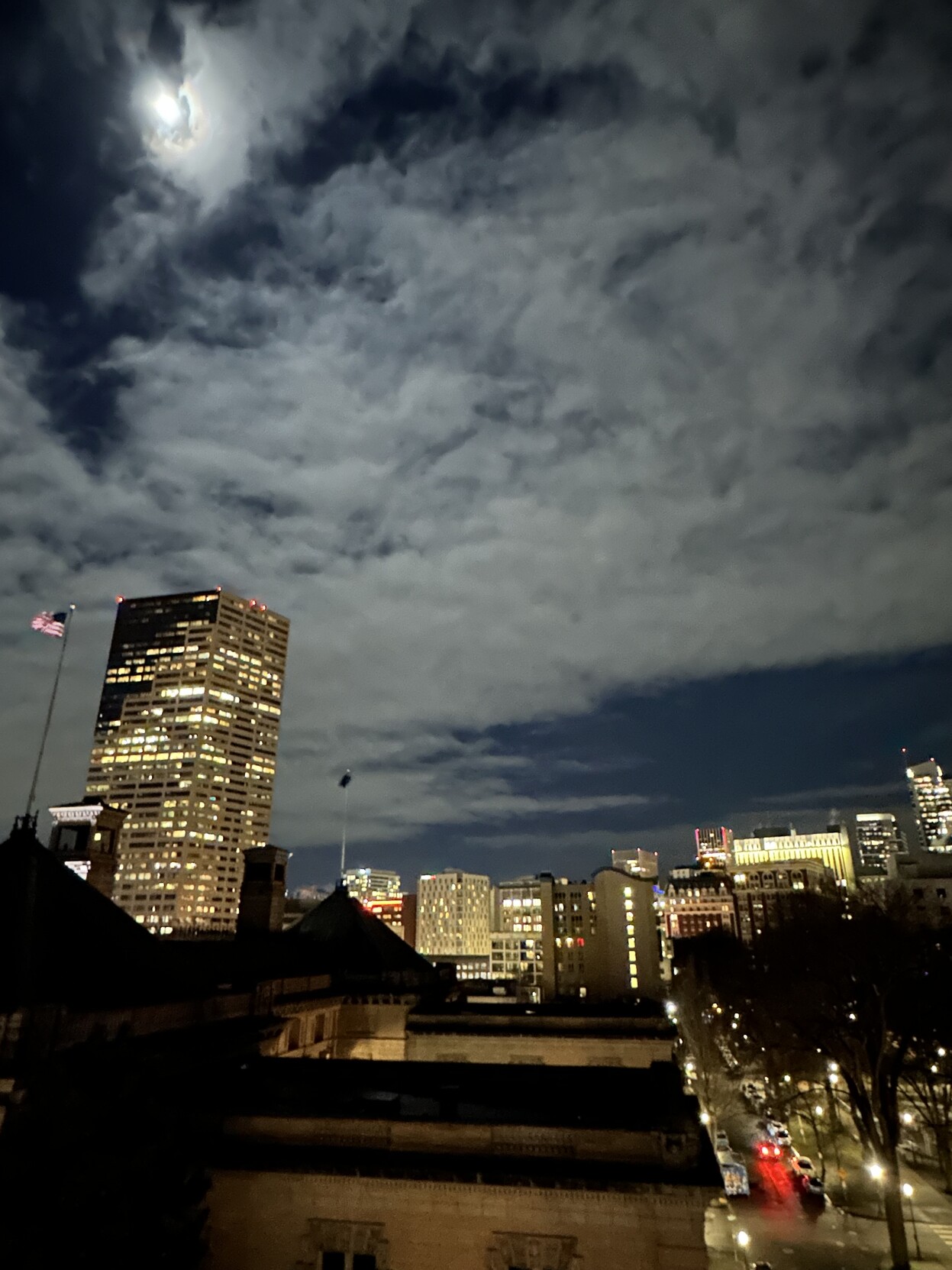 Night photograph of downtown Portland Ore. Moon backlighting the clouds. Buildings along the horizon.